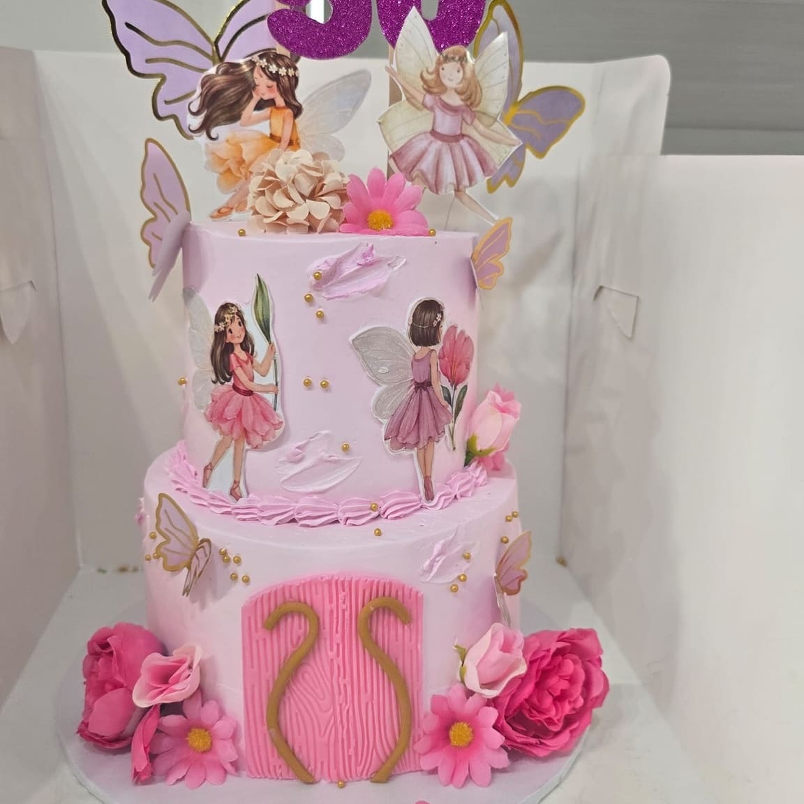 Two tier pink fairy cake for a 50th birthday with butterflies, roses and a glitter 50 topper