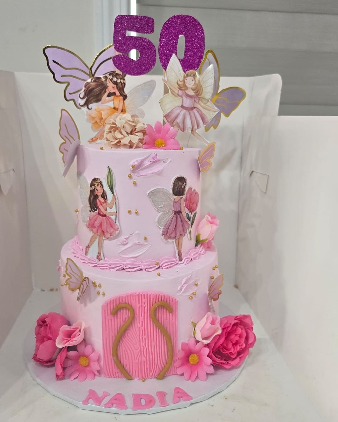 Two tier pink fairy cake for a 50th birthday with butterflies, roses and a glitter 50 topper