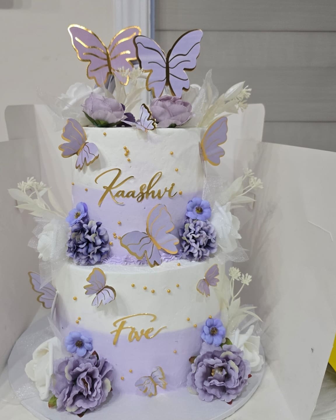Two tier lilac birthday cake with purple roses, lilac butterfly toppers and gold lettering for a fifth birthday