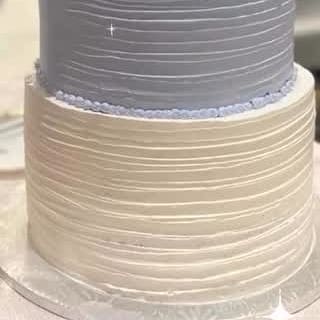 Combed buttercream tiers in white and soft grey on a tall wedding cake